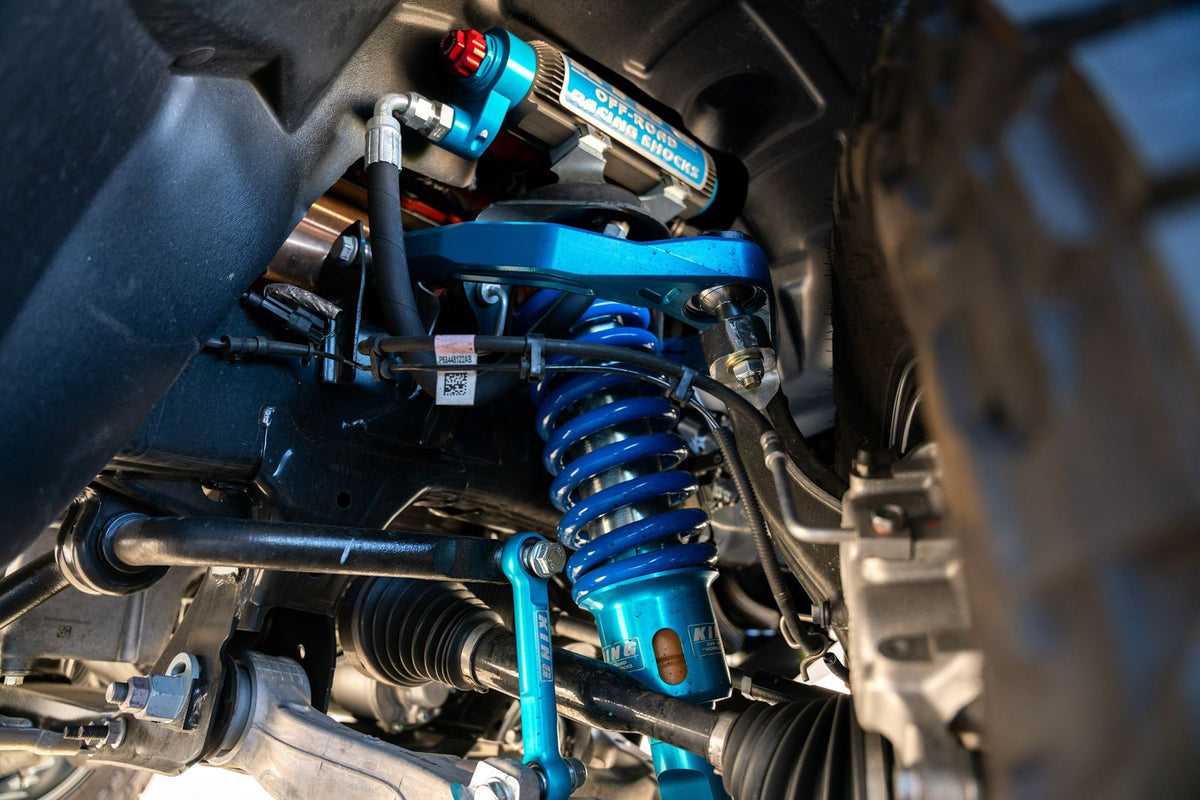 Blue coilover and upper control arm installed on a lifted truck