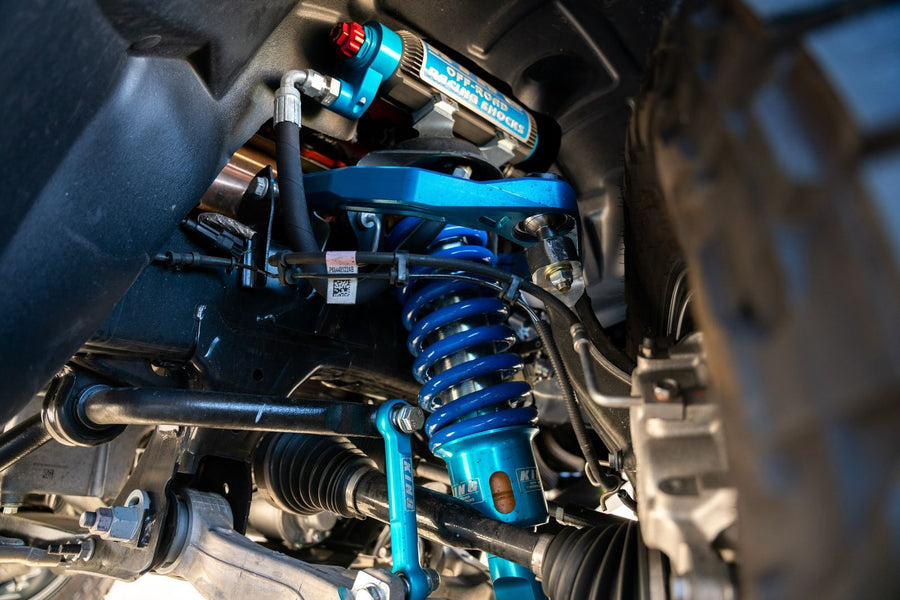 Blue coilover and upper control arm installed on a lifted truck