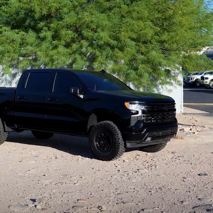 Black Chevrolet Silverado pickup parked on a dirt lot
