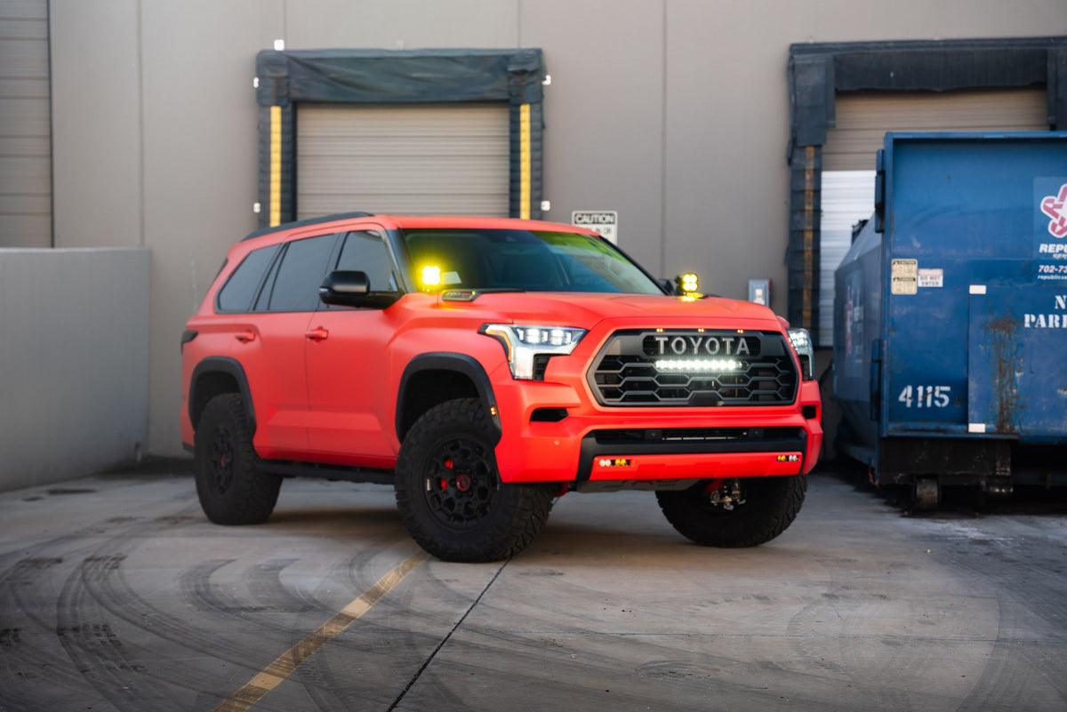 Red Toyota Sequoia with auxiliary lights at the shop's loading bay door