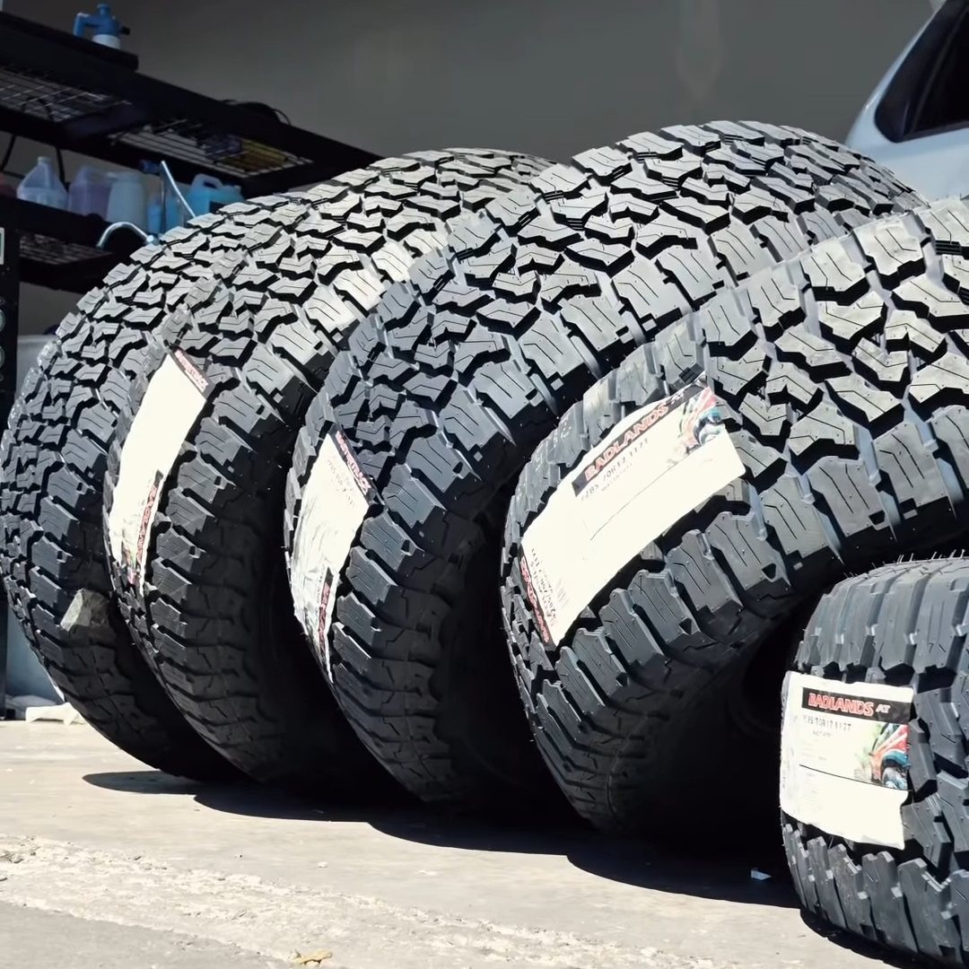 Set of new all-terrain tires with labels still on, lined up outside the shop