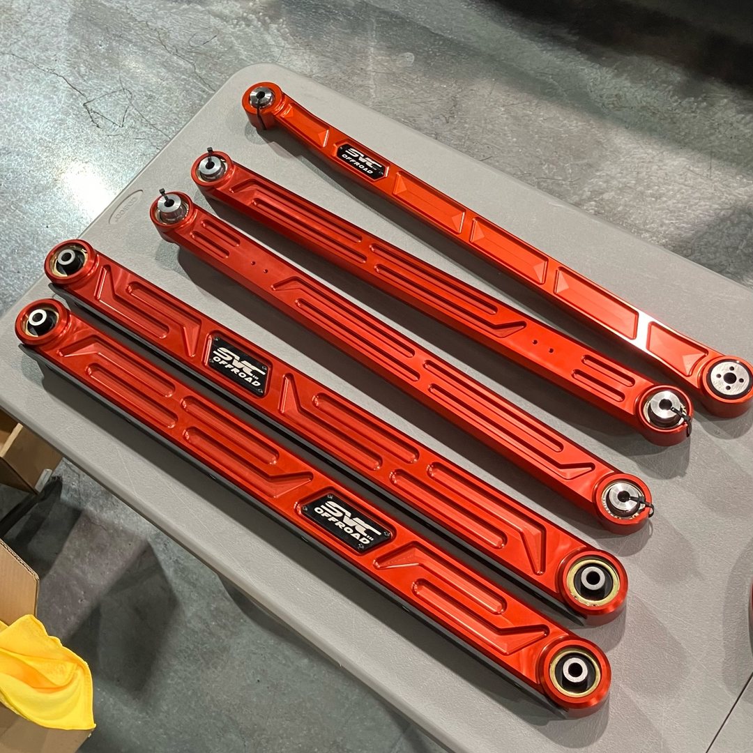 Set of orange SVC Off-Road aftermarket suspension links laid out on a table