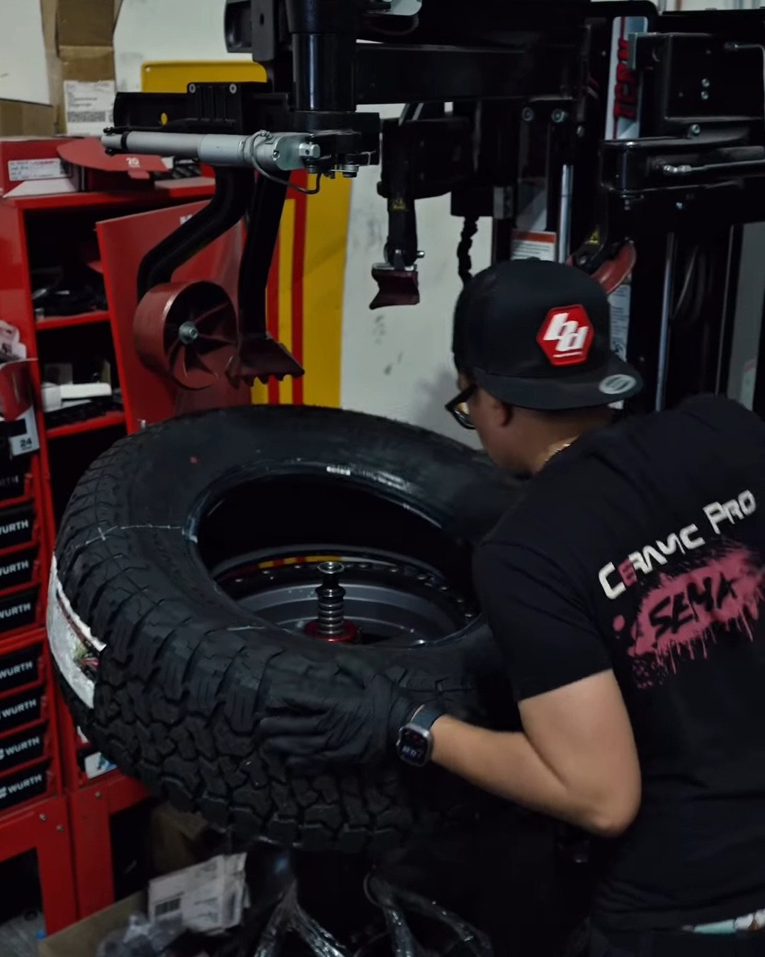 Technician mounting a new off-road tire on a wheel using a tire changer in the shop